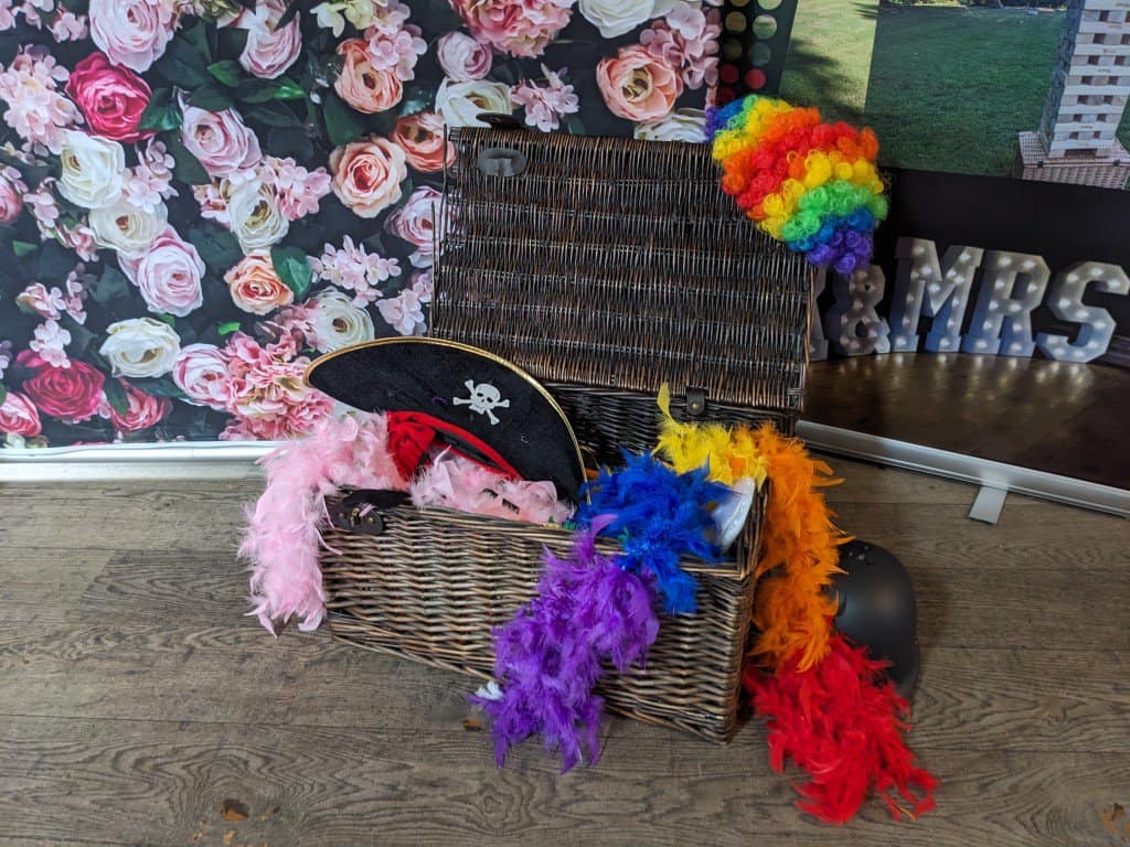 Colourful feather boas and pirate hat in basket at event.