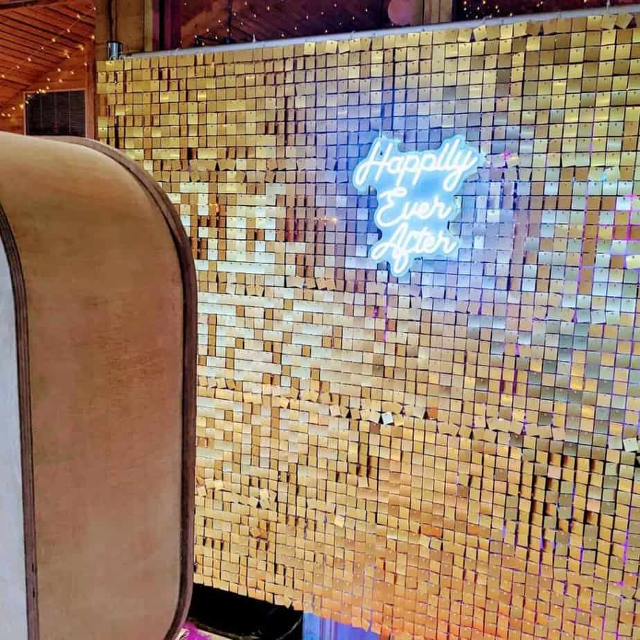 Neon 'Happily Ever After' sign on gold backdrop.