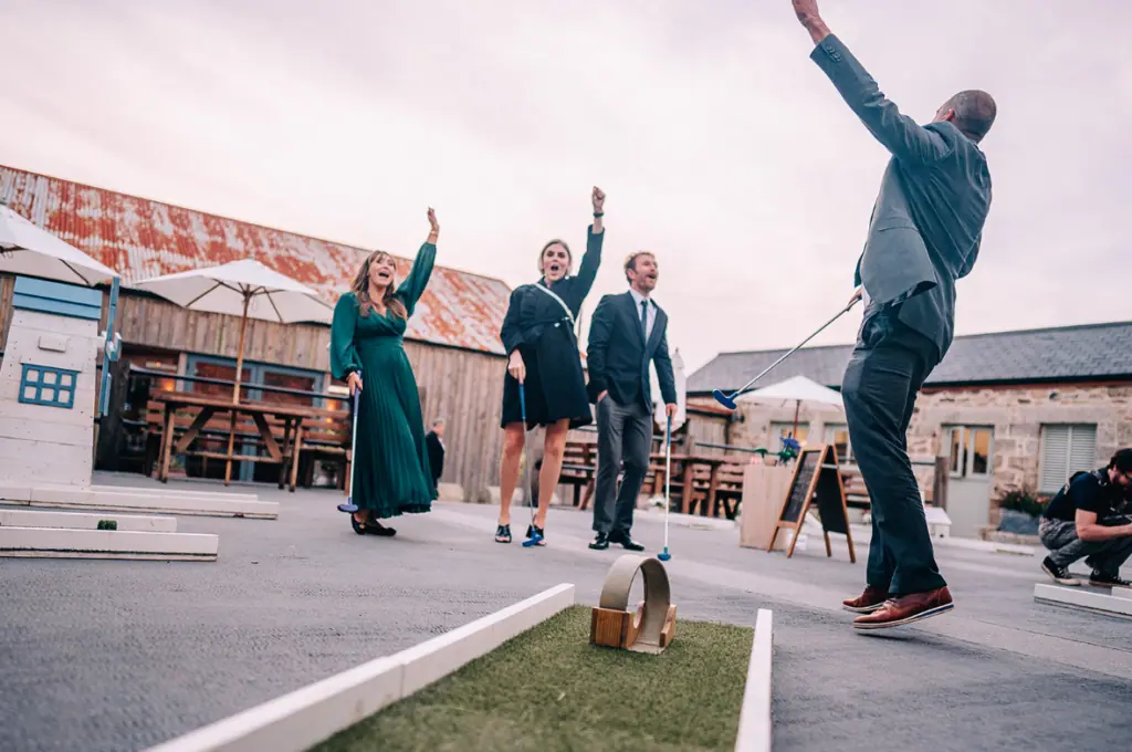 Group celebrating mini-golf win on outdoor course.